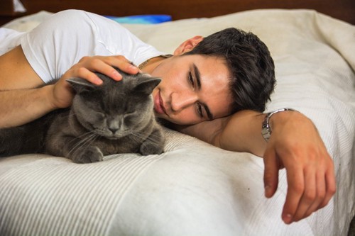 ベッドの上の男性と猫