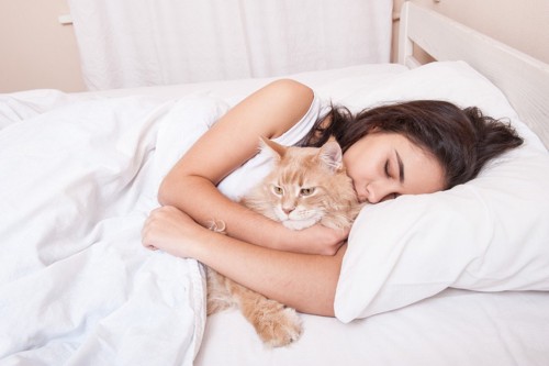 猫を抱きしめながら寝る女性