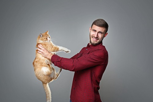 猫を遠目に抱っこをする男性