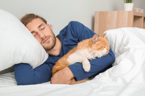 猫と一緒に眠る男性