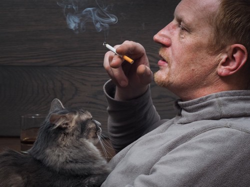 猫のそばで喫煙する男性