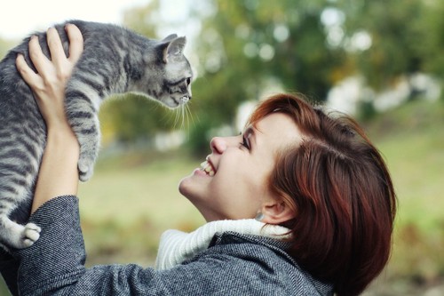 猫を抱き上げる笑顔の女性