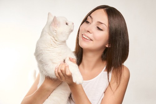 笑顔の女性に抱っこされている白猫