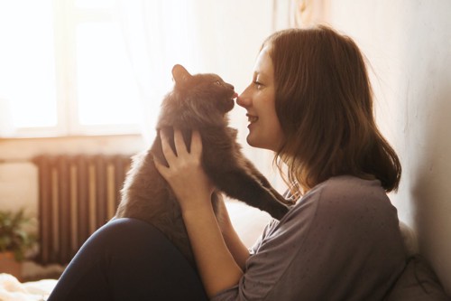 女性の鼻を舐める猫