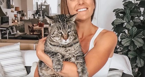 家の中でキジトラ猫を抱っこする女性
