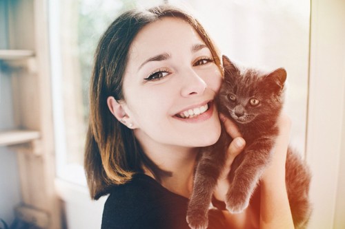 子猫を抱き上げた笑顔の女性