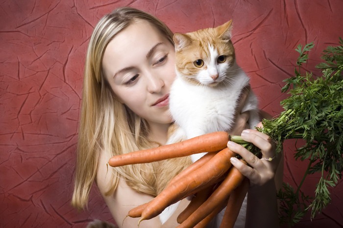 猫と人参を抱える女性