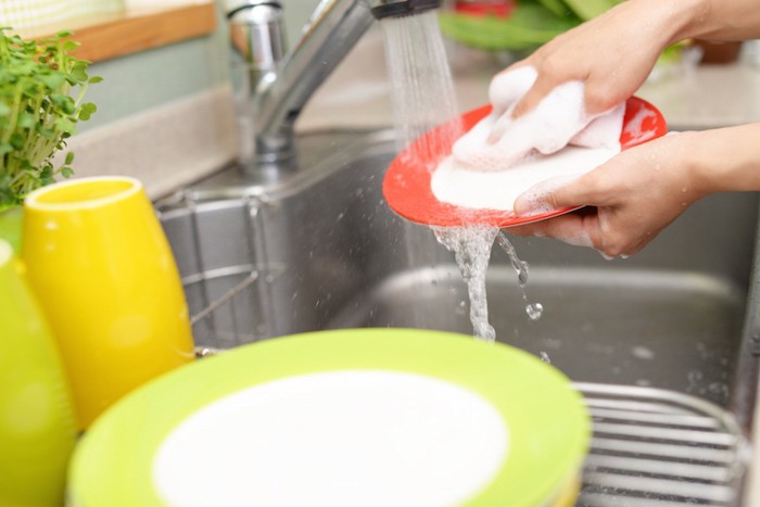 洗剤で食器を洗う人の手