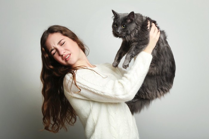 猫を抱っこする猫アレルギー持ちの女性