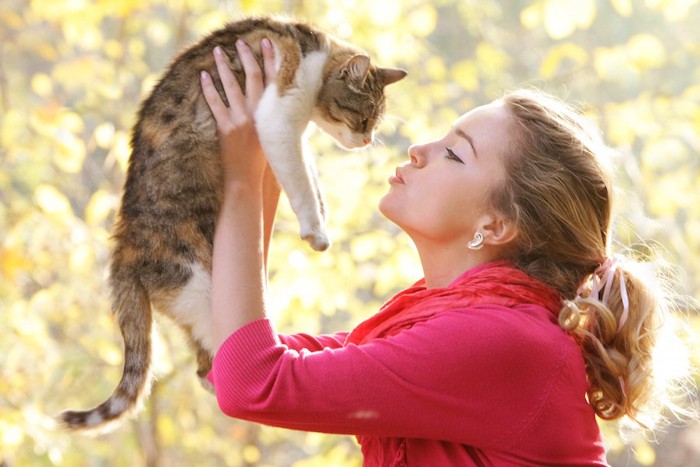 猫を抱き上げてキスをしようとする女性