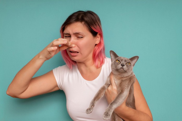 猫を抱いて鼻をつまむ女性