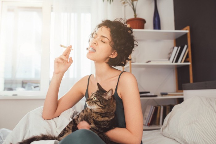 タバコを吸っている女性に抱かれている猫