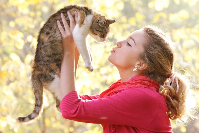 猫を抱き上げてキスする女性