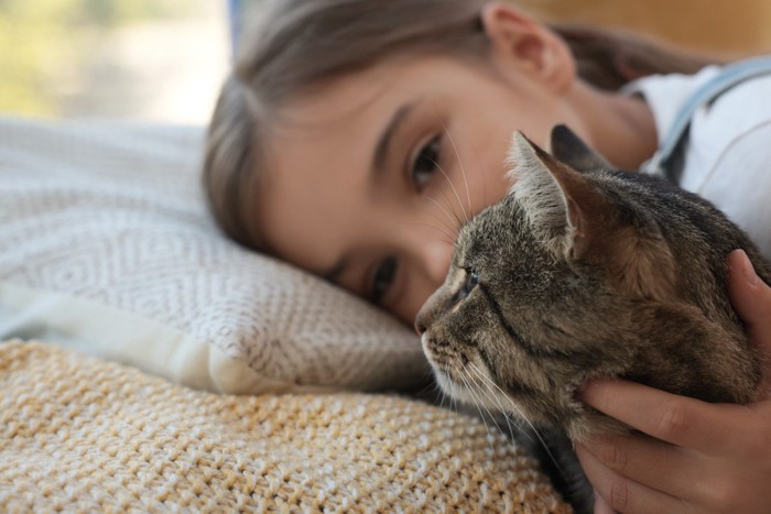 布団の中の猫と少女