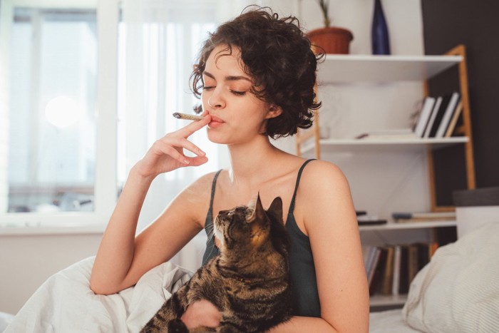 タバコを吸う女性に抱かれている猫