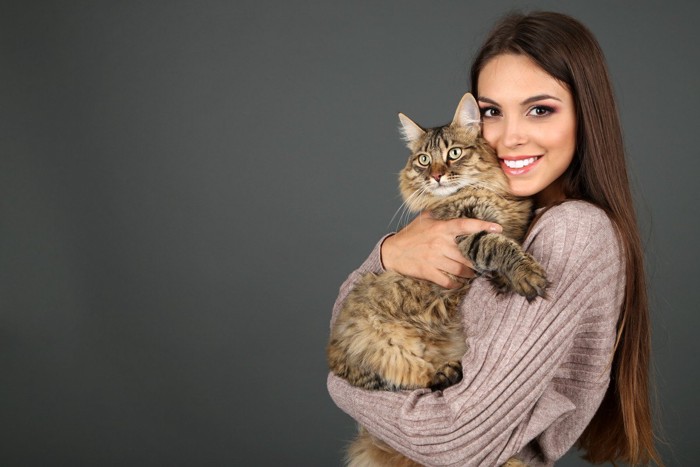 女性に抱っこされる猫