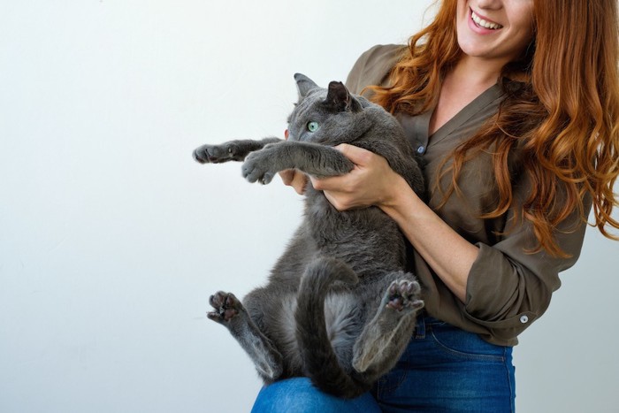 嫌がる猫を抱き上げる女性