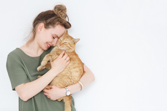 猫を抱っこして顔を近づける女性