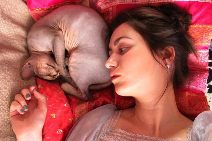女性の顔の近くで寝る猫