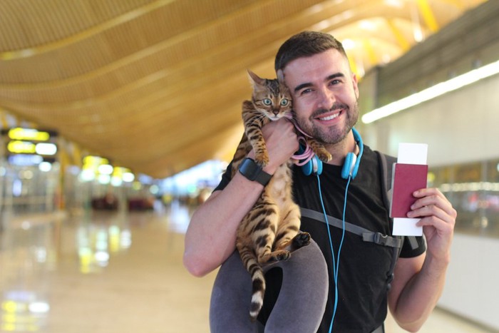 パスポートと猫を持った男性