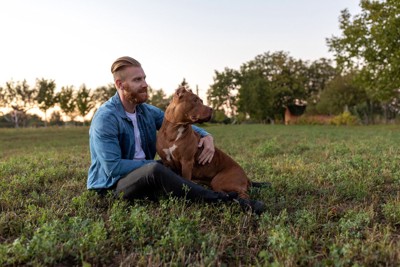 草の上に座る男性と犬