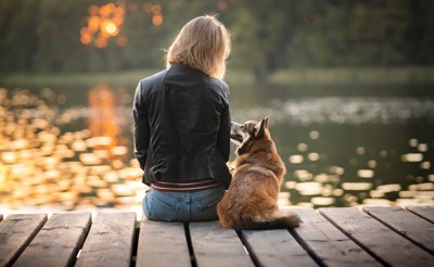 川辺に座る女性と犬