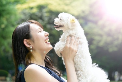 笑顔で犬を抱き上げる女性