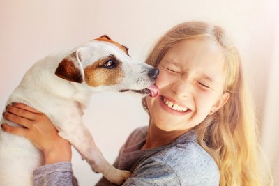 犬に顔を舐められている女の子