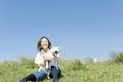芝生の上で座る女性と犬