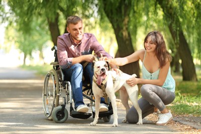 車椅子の男性と犬と女性