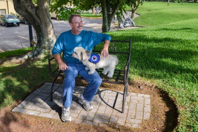 小型の介助犬とベンチに座る男性