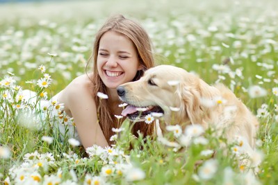 花畑で微笑む少女と犬