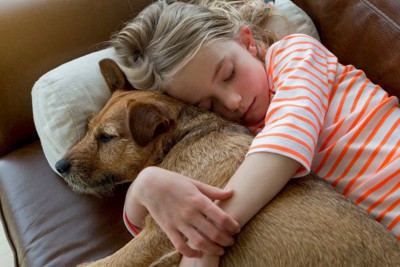 犬を抱きしめて寝る女の子