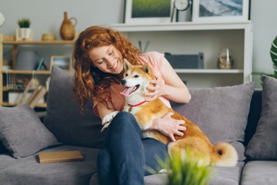 ソファーの上で触れ合う女性と犬
