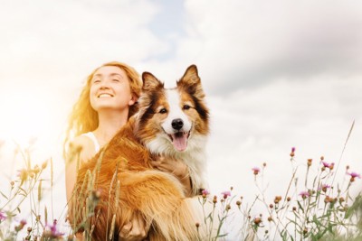 花に囲まれる犬と女性