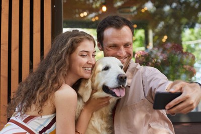 カフェに来た女性と写真を撮る犬と男性