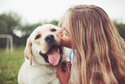 女性にキスされて嬉しそうな犬