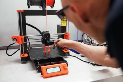 3Dプリンターをチェックする男性