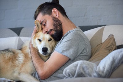 ソファーで犬を抱きしめる男性