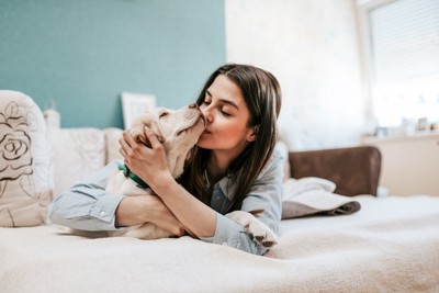 ベッドの上でキスする犬と女性