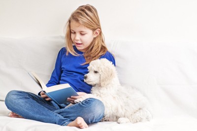 本を読む女の子と隣に座っている犬