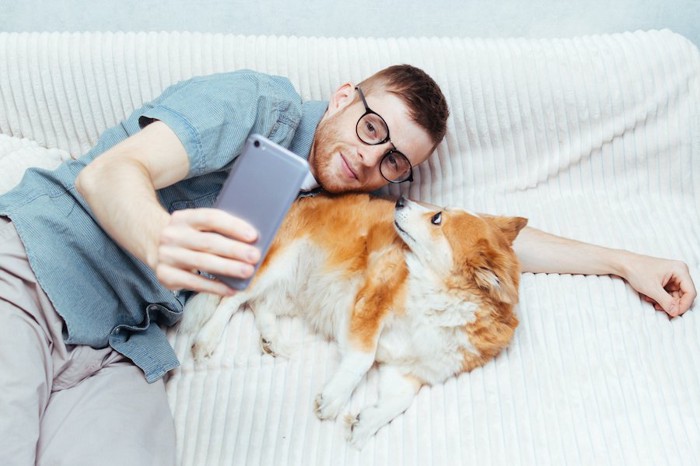 スマートフォンで犬と一緒に自撮りする男性