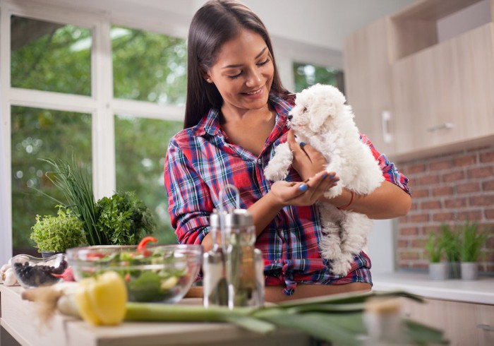 キッチンで犬を抱っこする女性