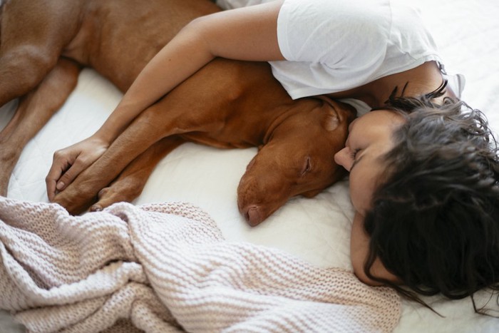 犬を抱きしめて一緒に眠る女性