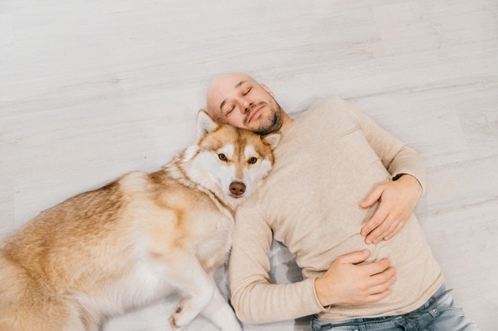 頭をくっつけて寝る犬と男性