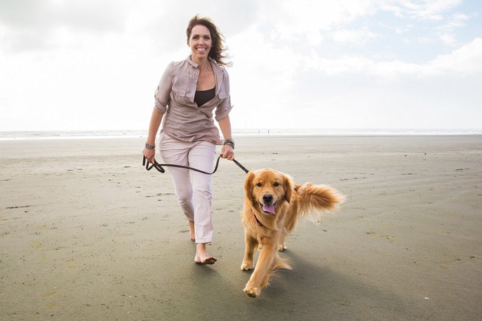 砂浜を散歩する女性と犬