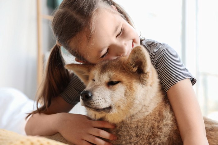 小さい女の子に抱きしめられる犬