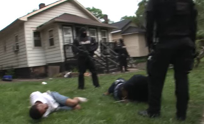 地面に横たわる逮捕者と監視する武装警官