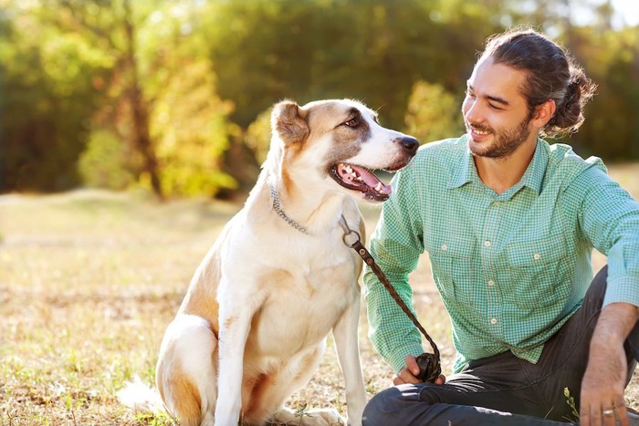 芝生に座る笑顔の男性と大型犬