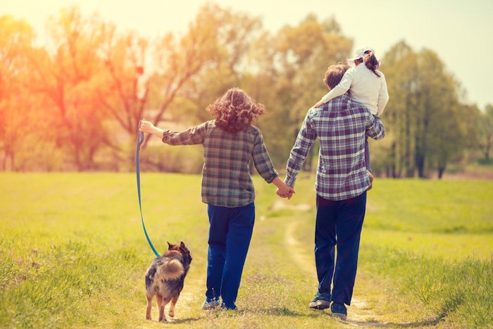 家族三人と散歩をする犬